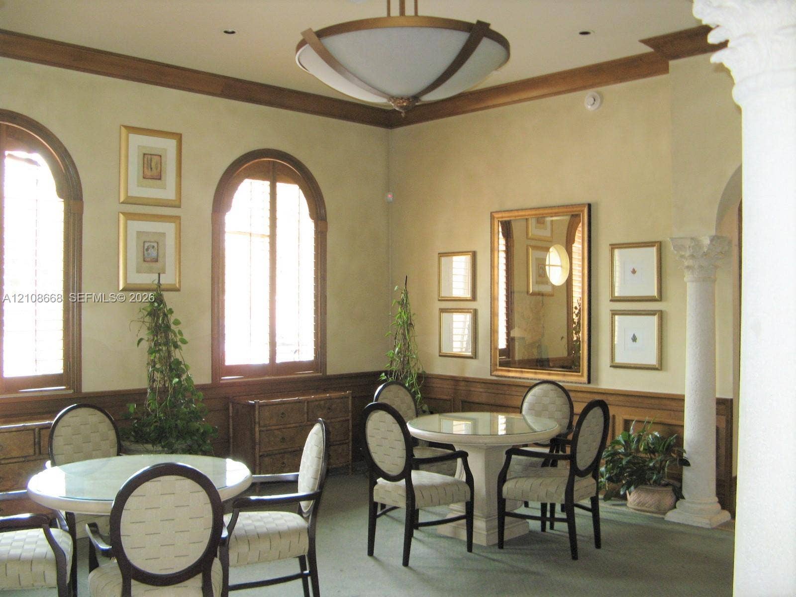 4508 SW 160th Avenue, #734, Miramar, Miramar, FL 33027 Interior space featuring arched windows with wood-trim detailing, decorative crown molding, a central modern chandelier, and a structural column with a Corinthian-style capital
