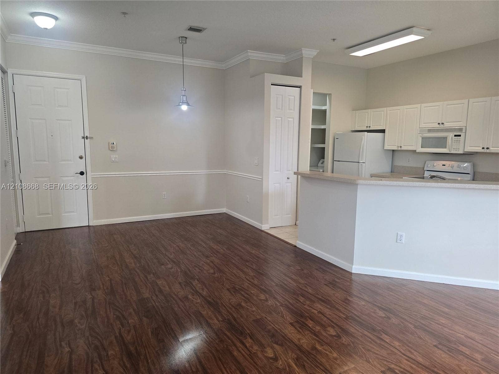 4508 SW 160th Avenue, #734, Miramar, Miramar, FL 33027 Open-concept area featuring wood-finish flooring, crown molding, chair rail detailing, white cabinetry, and a peninsula-style kitchen counter