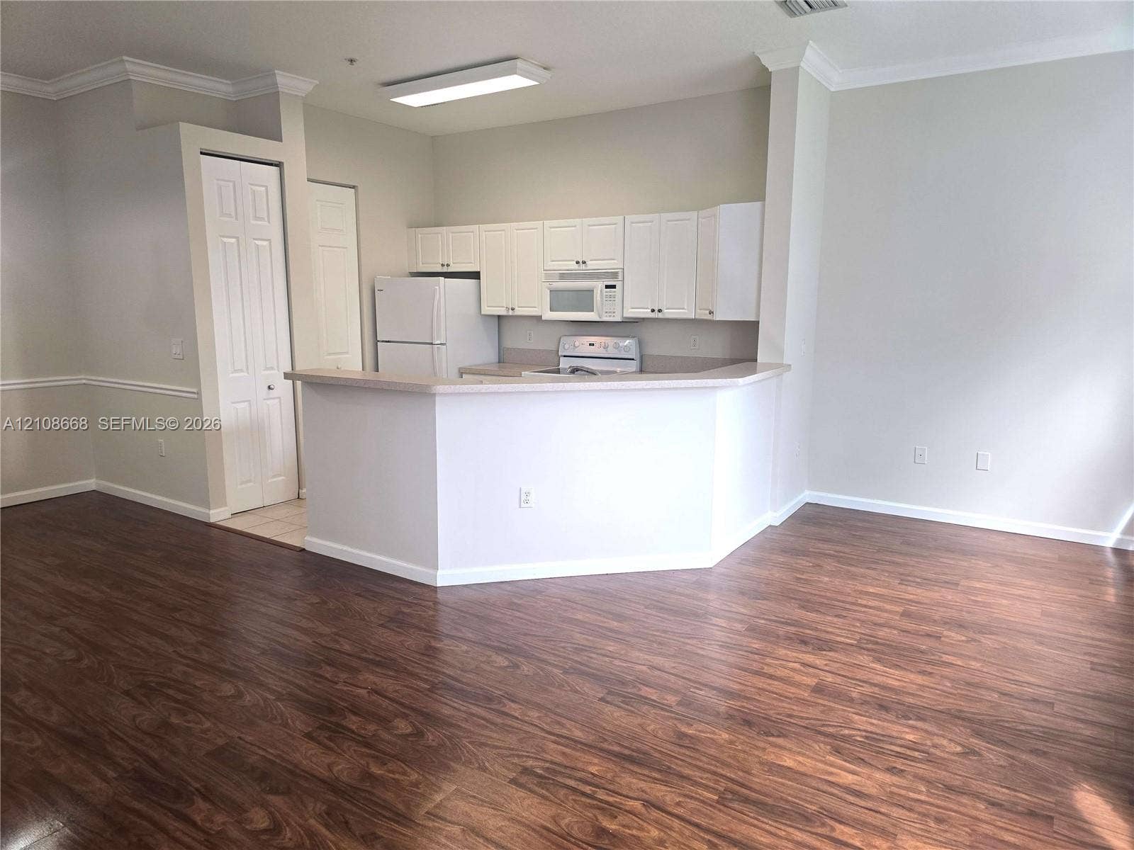 4508 SW 160th Avenue, #734, Miramar, Miramar, FL 33027 Kitchen featuring white cabinetry, wood-finish flooring, a breakfast bar, and neutral wall tones