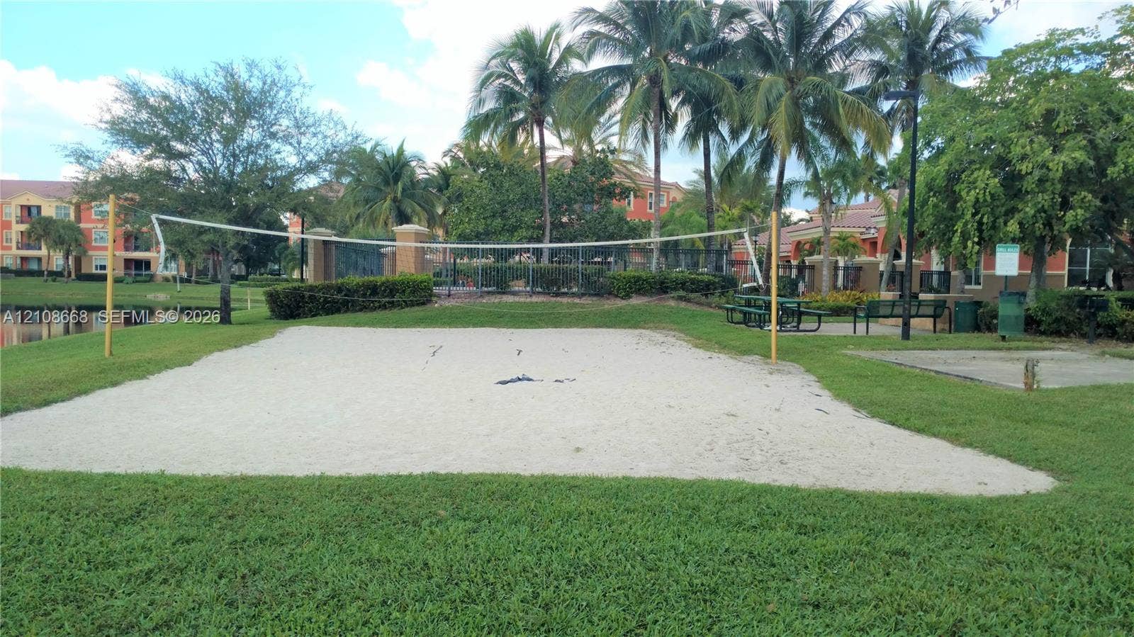 4508 SW 160th Avenue, #734, Miramar, Miramar, FL 33027 Sand volleyball court featuring a permanent net, manicured lawn, perimeter landscaping, and mature palm trees