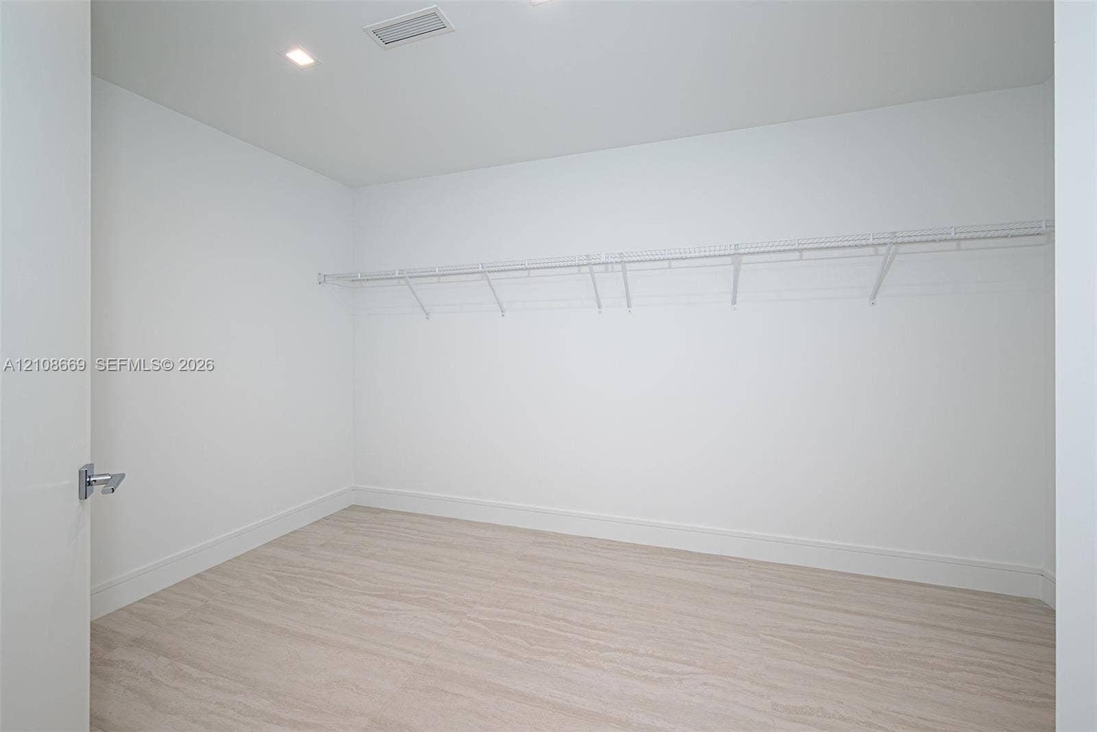 Walk-in closet featuring light wood-finish flooring, recessed lighting, and wall-mounted wire shelving