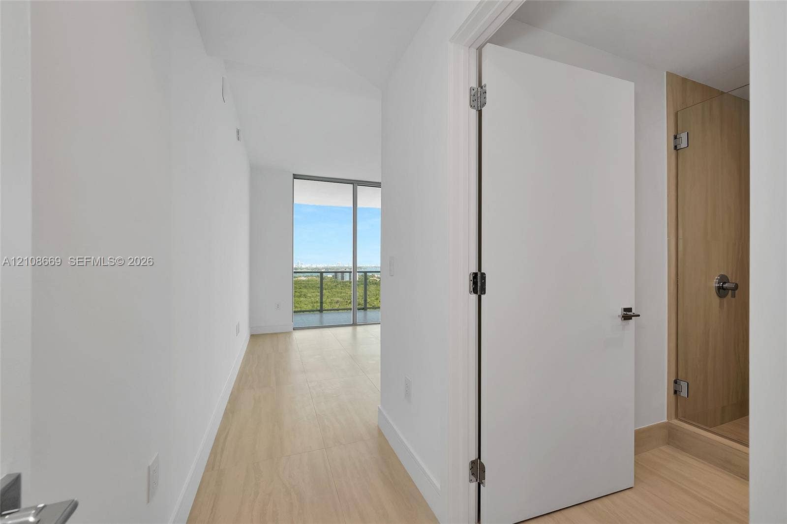 Interior featuring light wood-finish flooring, floor-to-ceiling glass sliding doors, and a glass-enclosed shower with wood-tone surround