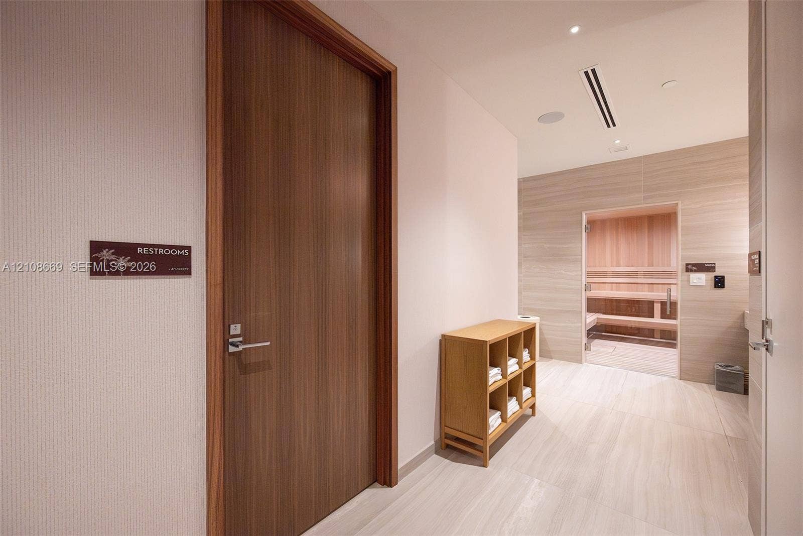 Sauna featuring interior wood paneling and integrated bench seating, complemented by large-format tile flooring and wood-finish doors