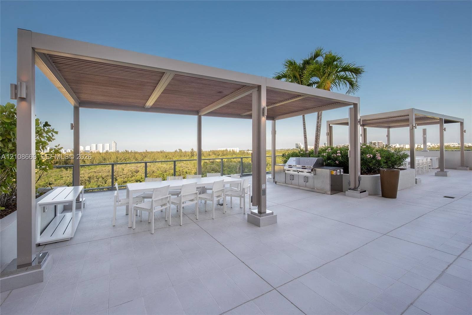 Rooftop terrace featuring large-format tile flooring, metal-framed pergolas with wood-finish ceilings, stainless steel outdoor kitchen, and glass railings