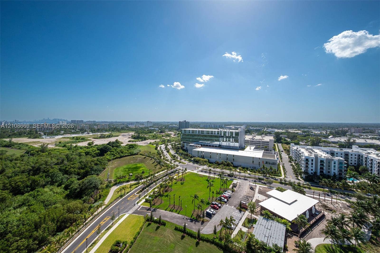 Aerial perspective featuring expansive green spaces, paved roadways, and surrounding urban infrastructure