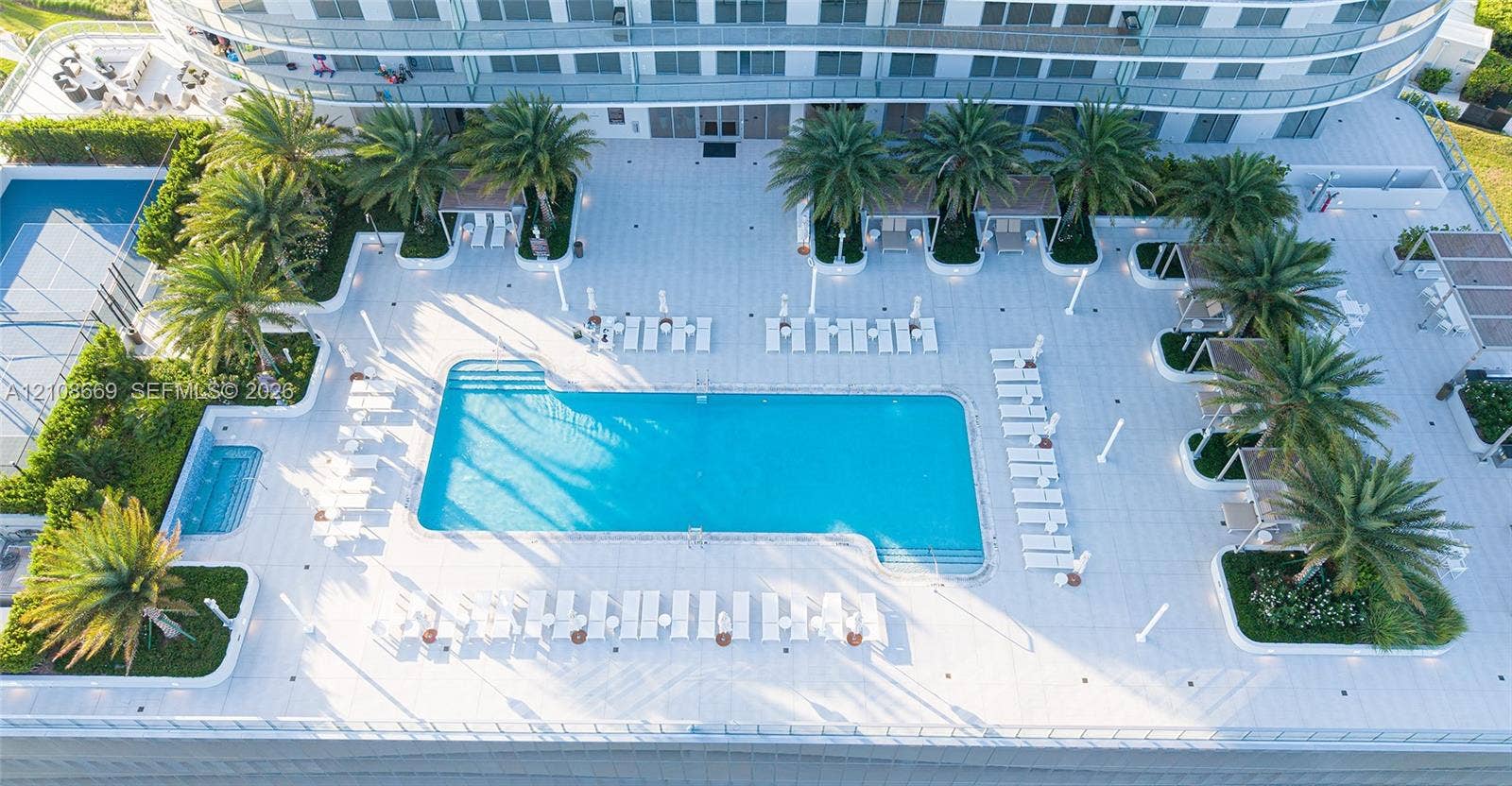 Swimming pool and separate spa with tile decking, integrated palm tree landscaping, and overhead structural balconies