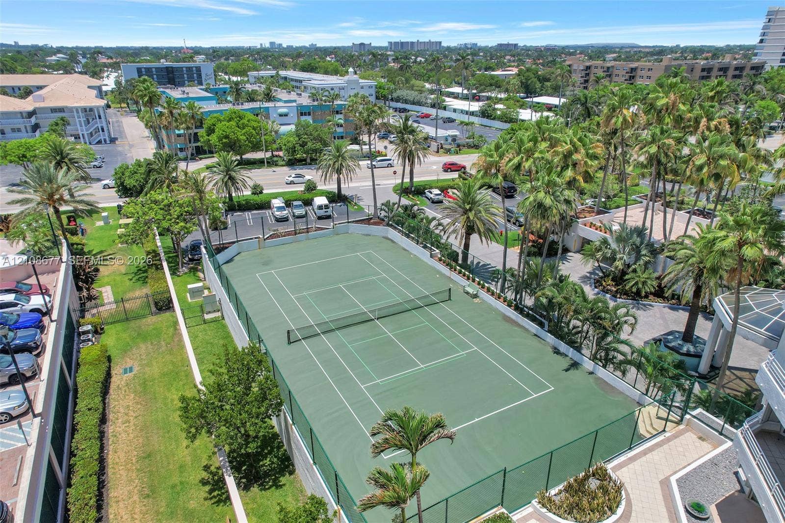 1440 S Ocean Boulevard, #11A, Lauderdale By The Sea, FL 33062 Fenced tennis court with a hard-surface finish, surrounded by mature palm trees and manicured landscaping