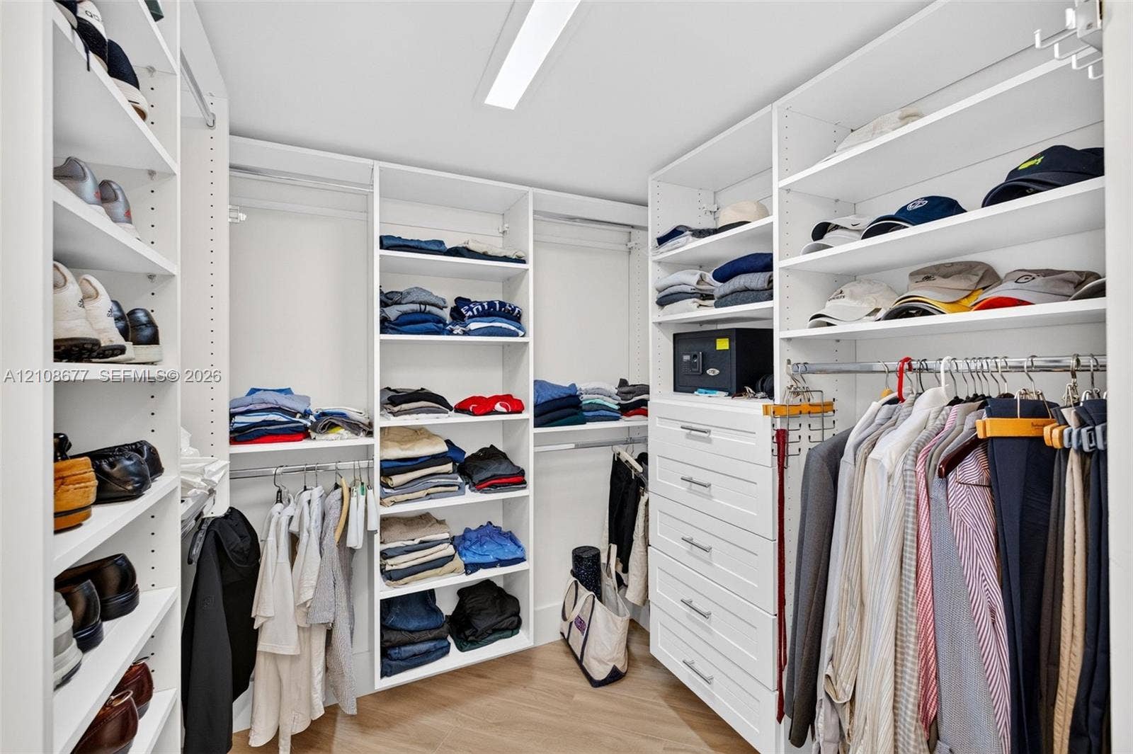 1440 S Ocean Boulevard, #11A, Lauderdale By The Sea, FL 33062 View toward shorter side of the custom walk-in closet featuring floor-to-ceiling white shelving, integrated clothing rods, stacked drawer storage, and wood look plank porcelain flooring
