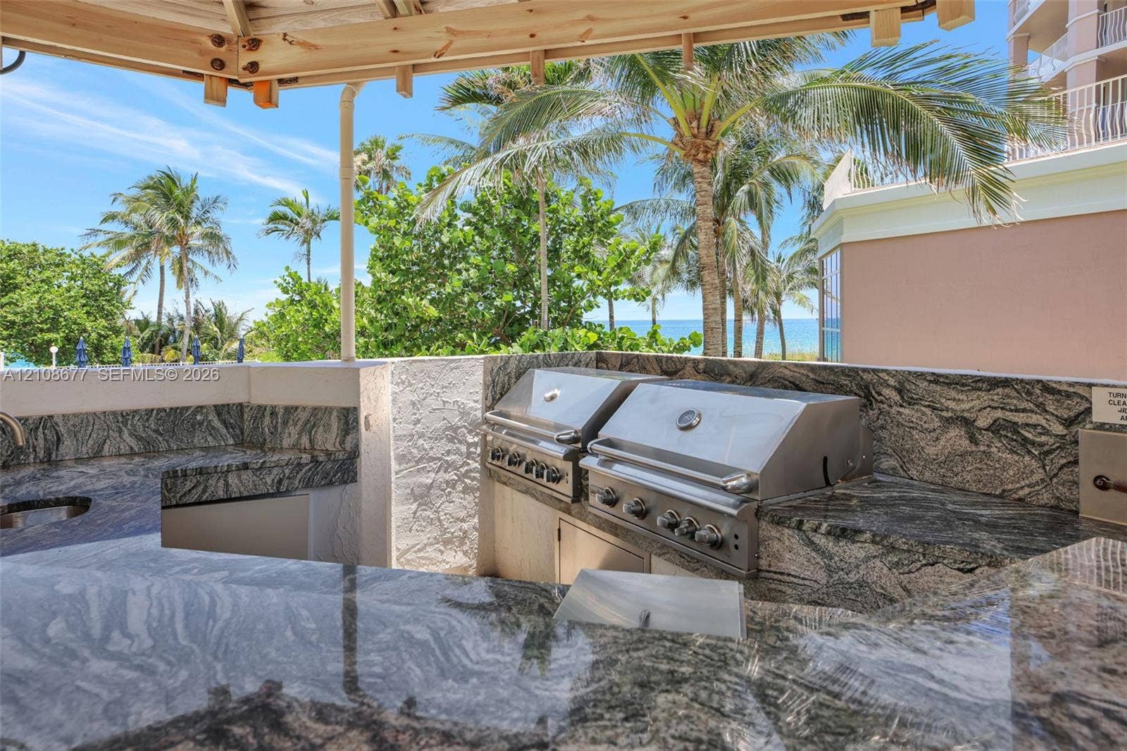 1440 S Ocean Boulevard, #11A, Lauderdale By The Sea, FL 33062 Outdoor BBQ kitchen featuring stone countertops, dual stainless steel built-in grills, a covered structure, and water views