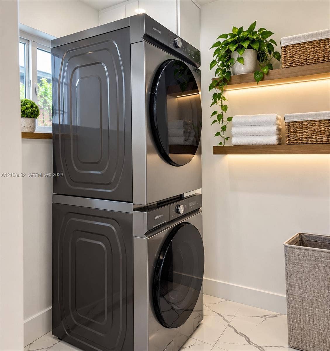 8943 NW 112th Terrace, Hialeah Gardens, FL 33018 Stacked stainless steel laundry appliances, floating wooden wall shelves with integrated lighting, and white flooring with dark veining
