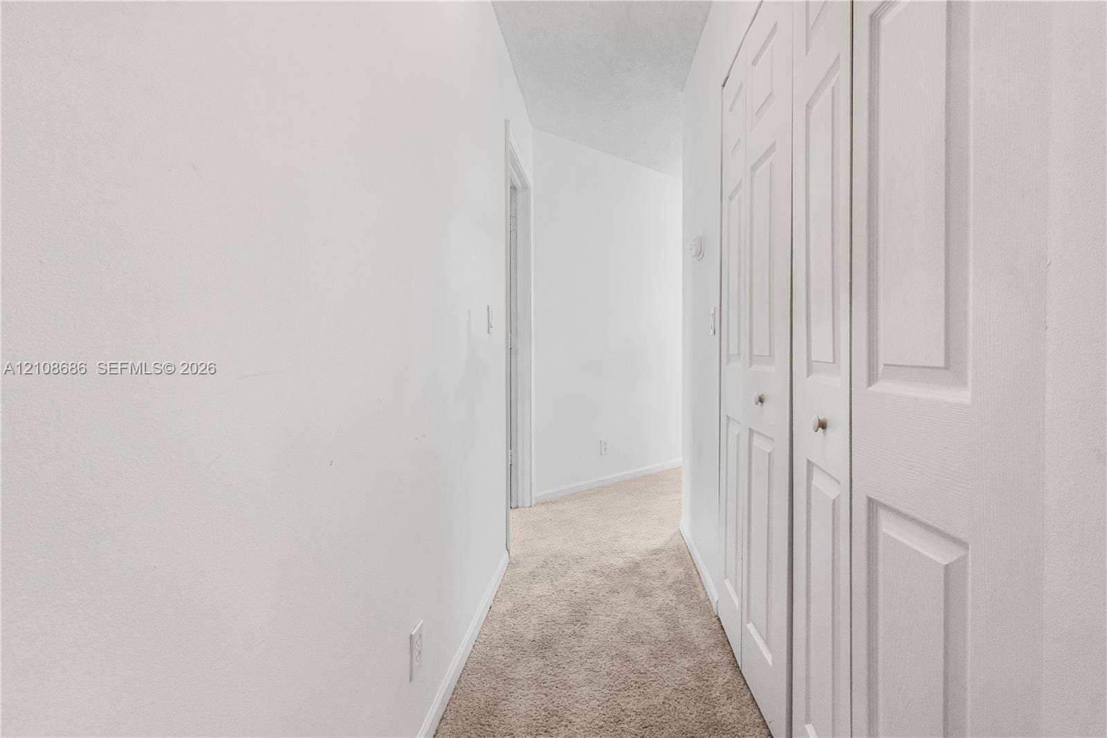 Hallway featuring wall-to-wall carpeting and bi-fold closet doors