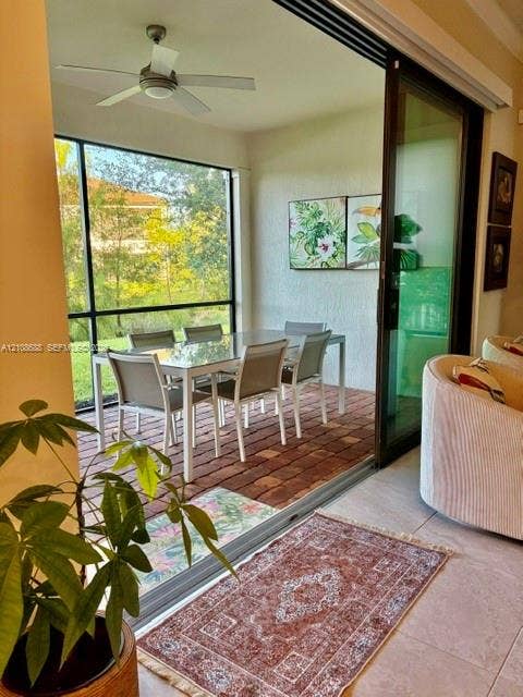 Screened lanai featuring brick paver flooring, a ceiling fan, and large-format sliding glass doors