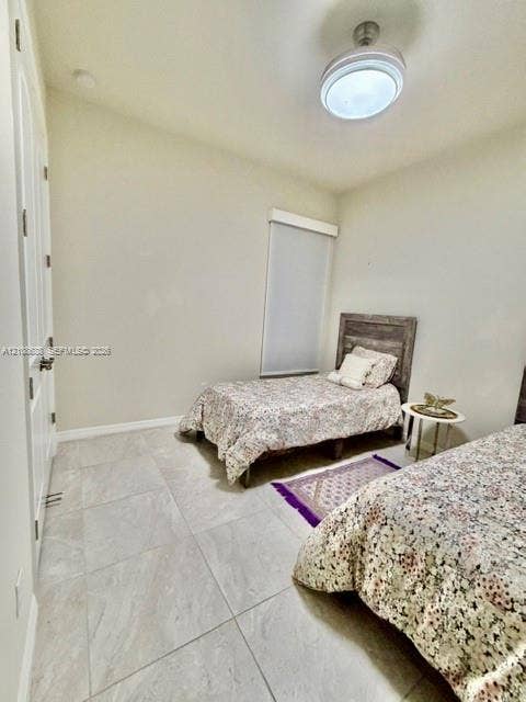 Large-format tile flooring, high ceilings, ceiling-mounted light fixture with fan, and a neutral wall finish