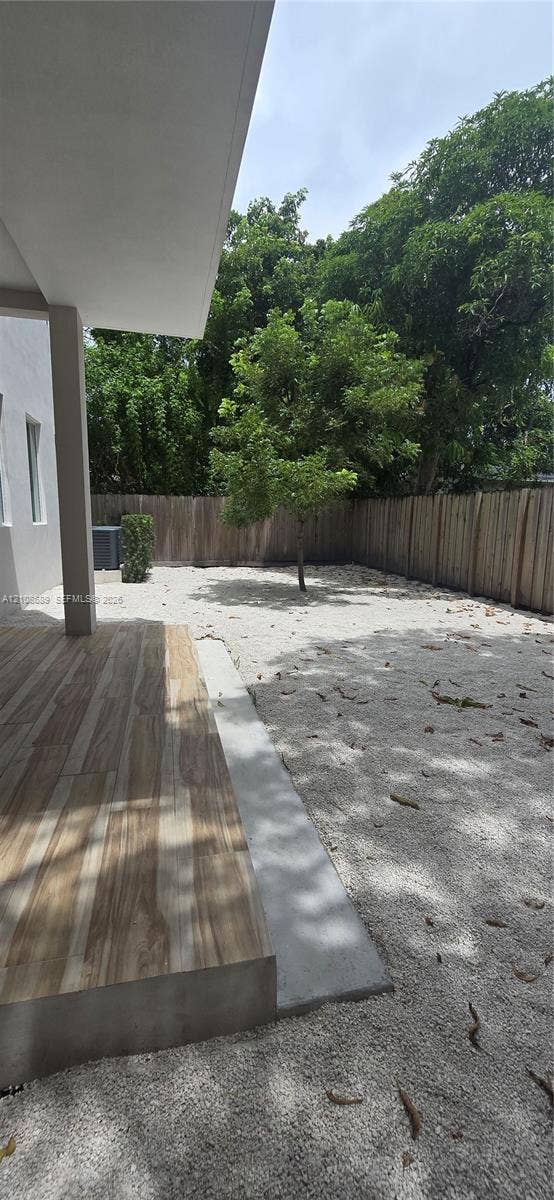 Miami, Miami, FL 33133 Covered patio with wood-finish tile flooring, fenced outdoor space with aggregate ground cover, and mature trees