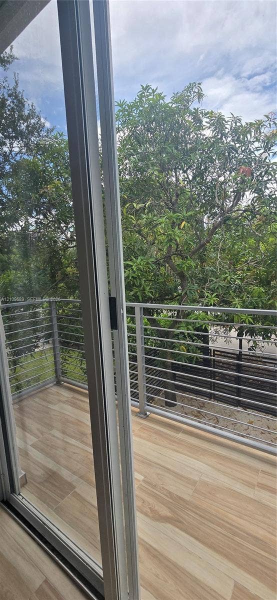 Miami, Miami, FL 33133 Balcony featuring wood-finish tile flooring, metal horizontal-bar railing, and floor-to-ceiling glass sliding doors
