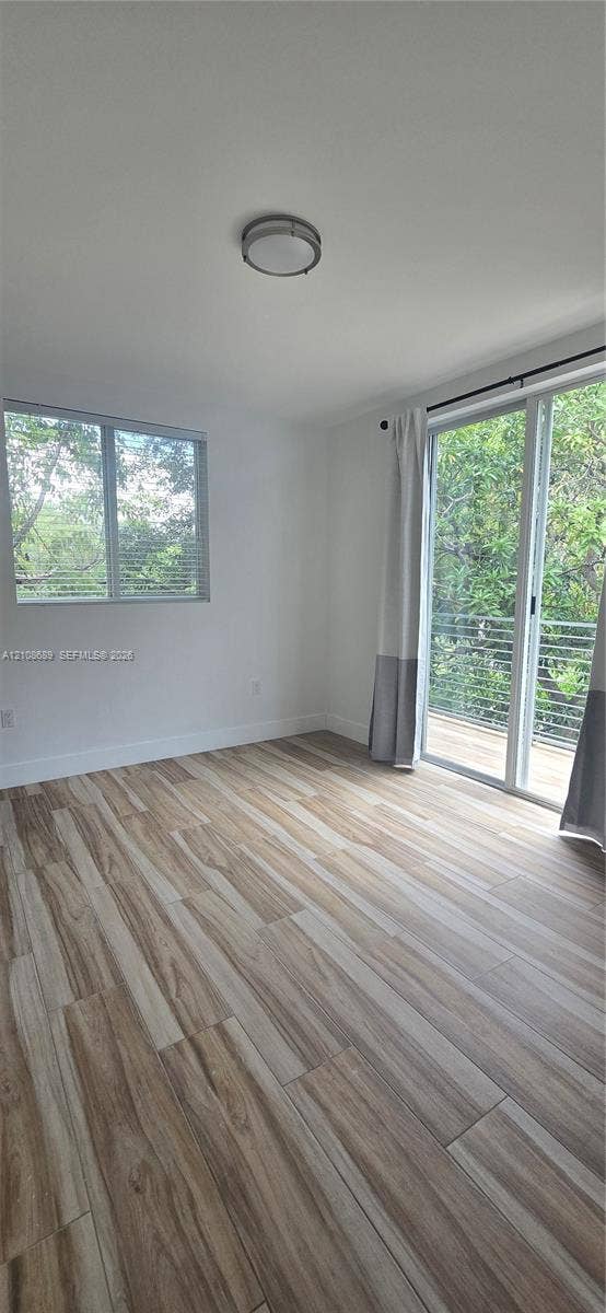Miami, Miami, FL 33133 Wood-finish flooring, sliding glass door with external railing, single-hung window, and flush-mount ceiling lighting