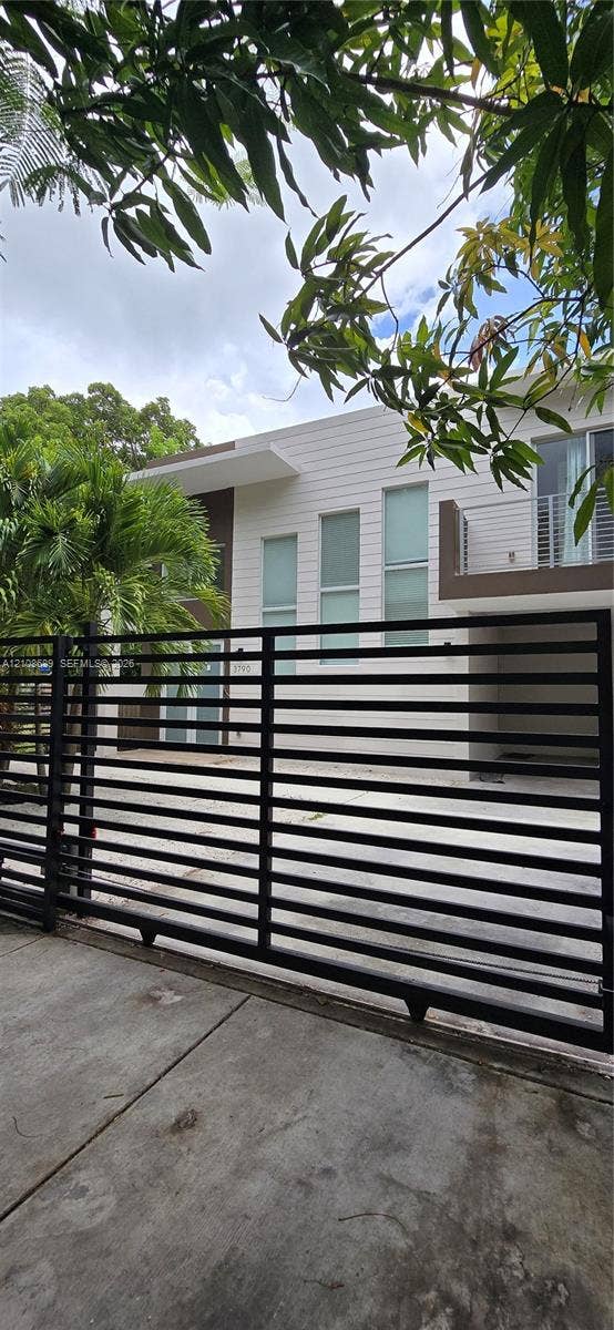 Miami, Miami, FL 33133 Modern two-story exterior featuring horizontal siding, a private gated entrance, tall vertical windows, and a metal-railing balcony