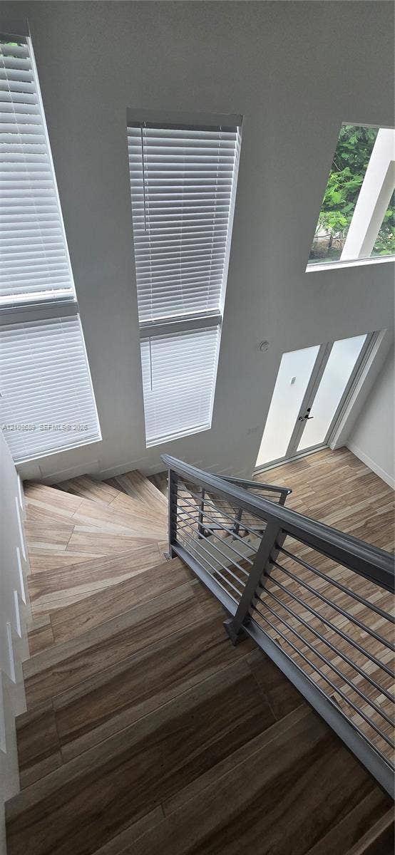 Miami, Miami, FL 33133 Staircase featuring wood-finish flooring, metal cable railing, floor-to-ceiling windows, and frosted glass paneled door