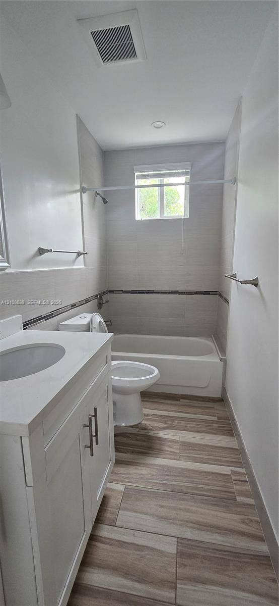 Miami, Miami, FL 33133 White vanity with a stone-finish countertop, wood-finish tile flooring, and tiled shower surround with decorative mosaic accent