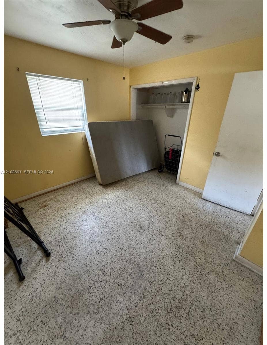 17210 NW 47th Avenue, Miami Gardens, FL 33055 Interior space featuring terrazzo flooring, a ceiling fan with light fixture, a single-hung window with blinds, and a built-in closet with shelving