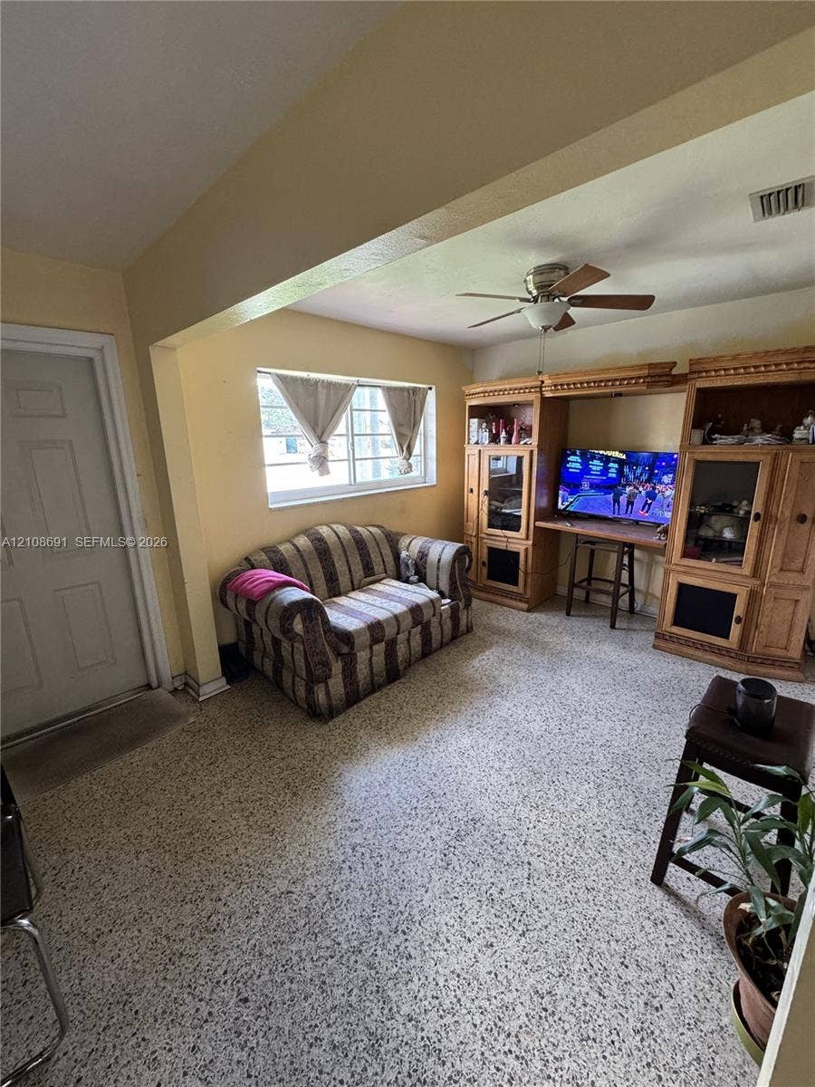 17210 NW 47th Avenue, Miami Gardens, FL 33055 Living space featuring built-in wooden cabinetry, multi-pane window, ceiling fan with light fixture, and terrazzo flooring