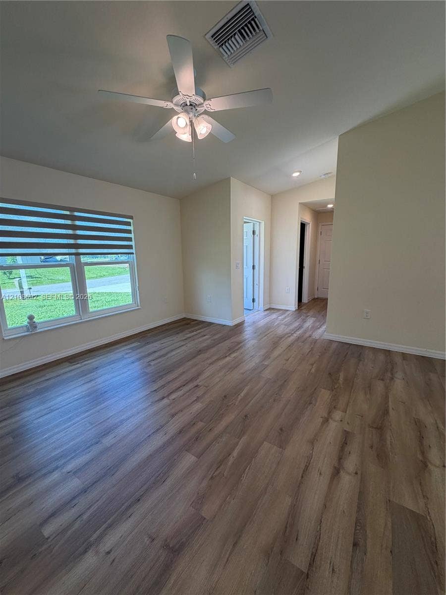Wood-finish flooring throughout, vaulted ceilings, and a central ceiling fan with integrated lighting