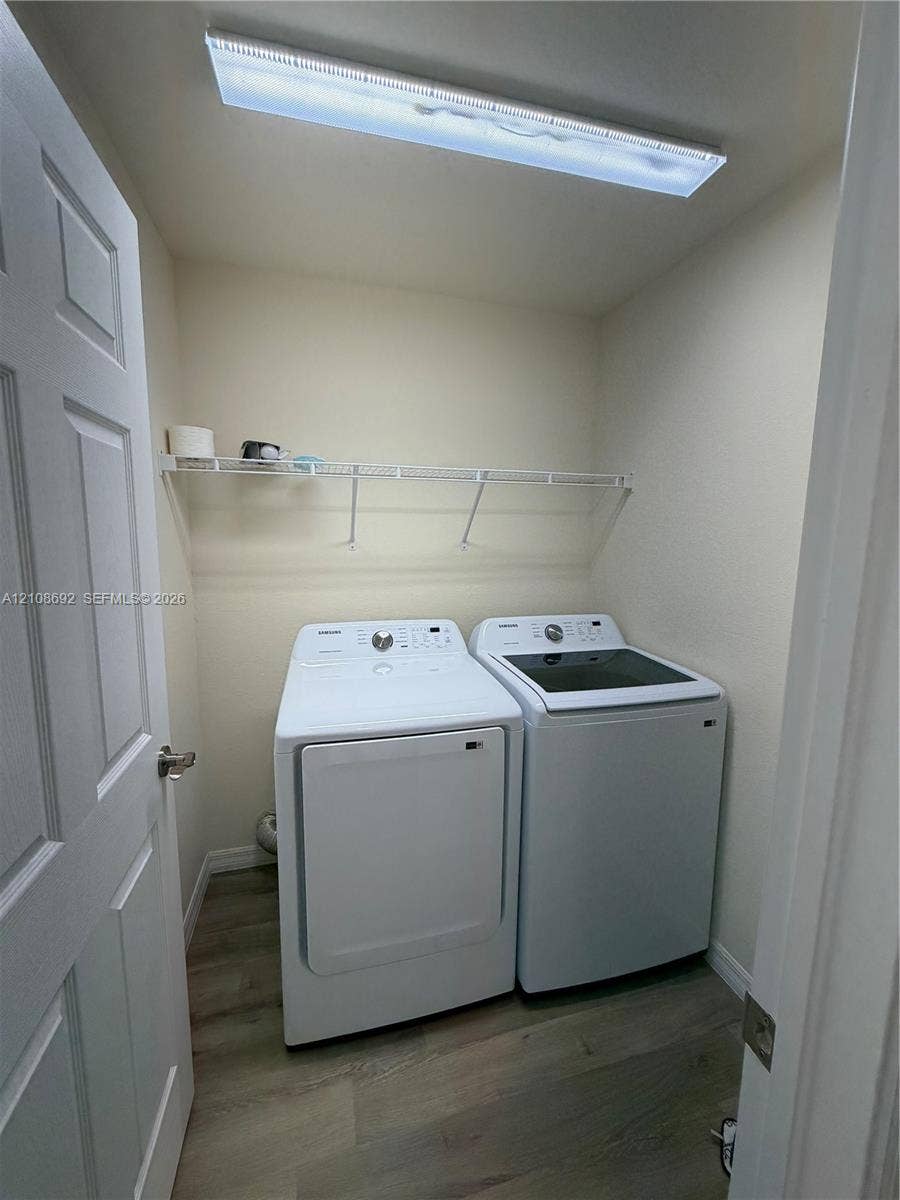 Laundry area featuring wood-finish flooring, white paneled door, and wall-mounted wire shelving