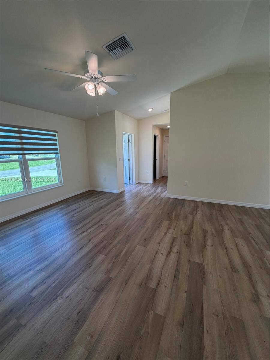 Vaulted ceilings, wood-finish flooring, ceiling fan with integrated lighting, and multi-paned windows featuring adjustable blinds