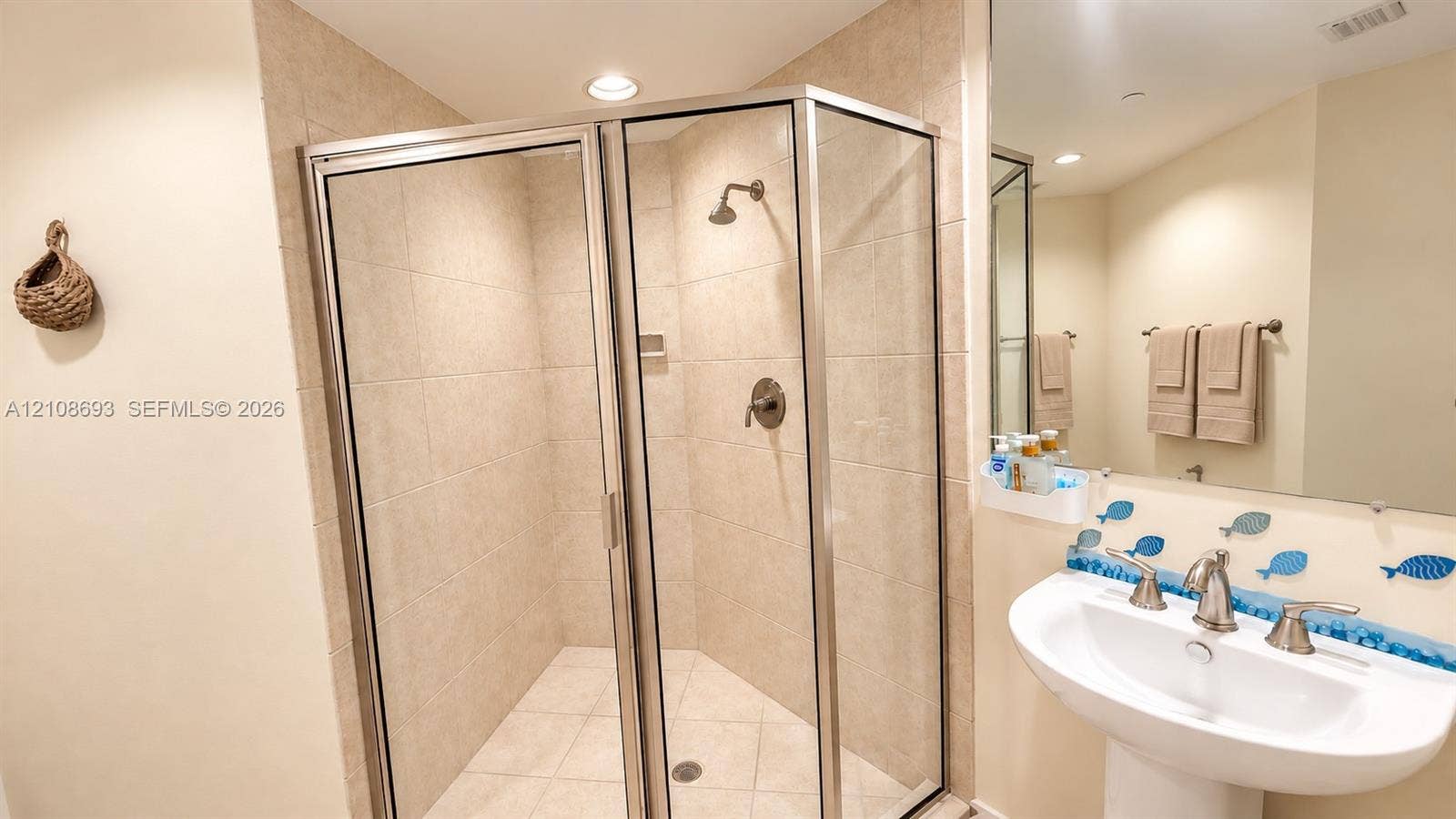 231 Riverside Drive, #1210, Daytona Beach, Daytona Beach, FL 32117 Walk-in corner shower with a glass enclosure, ceramic tile surround, pedestal sink with metallic fixtures, and a wall-mounted mirror
