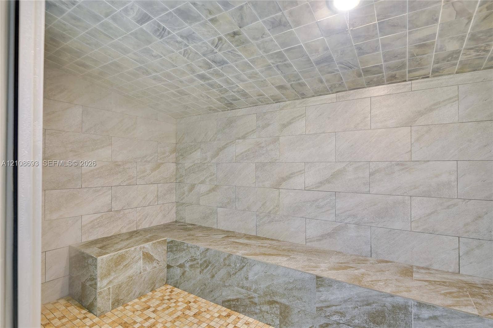 231 Riverside Drive, #1210, Daytona Beach, Daytona Beach, FL 32117 Enclosed sauna featuring large-format stone-style wall tile, a built-in stone-style bench, mosaic-tile flooring, and a tiled vaulted ceiling