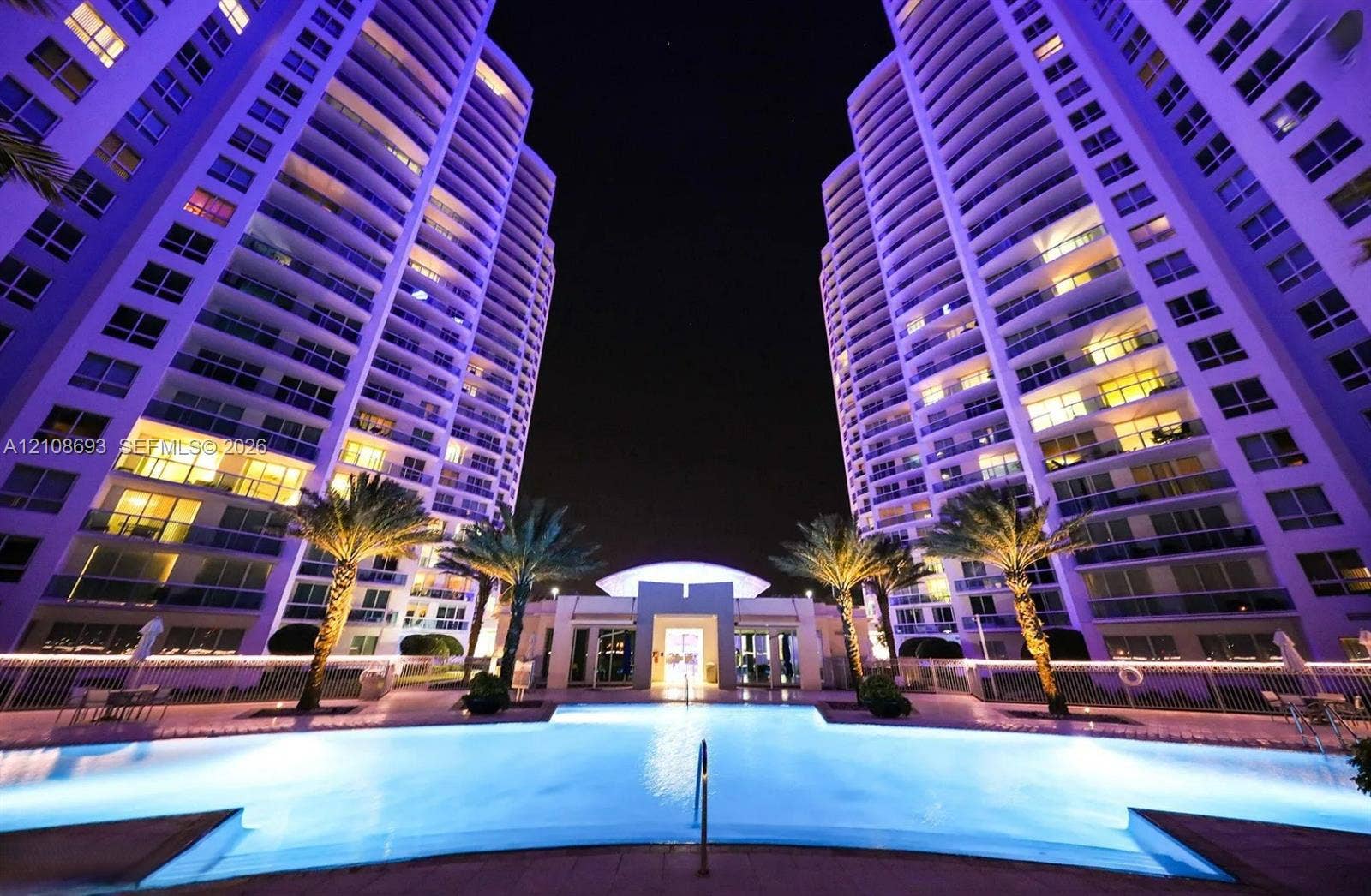 231 Riverside Drive, #1210, Daytona Beach, Daytona Beach, FL 32117 Swimming pool with surrounding paver deck, palm trees, and high-rise tower exteriors featuring expansive balconies