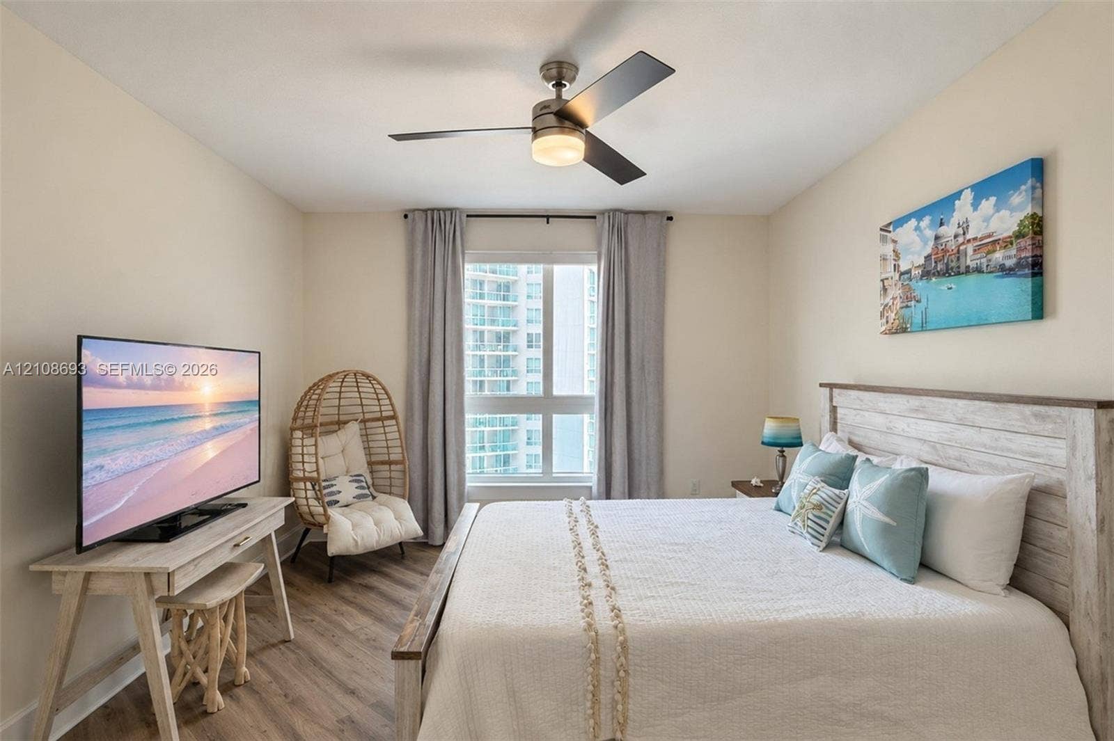 231 Riverside Drive, #1210, Daytona Beach, Daytona Beach, FL 32117 Wood-finish flooring, multi-pane window with neutral drapery, and a contemporary ceiling fan with integrated lighting