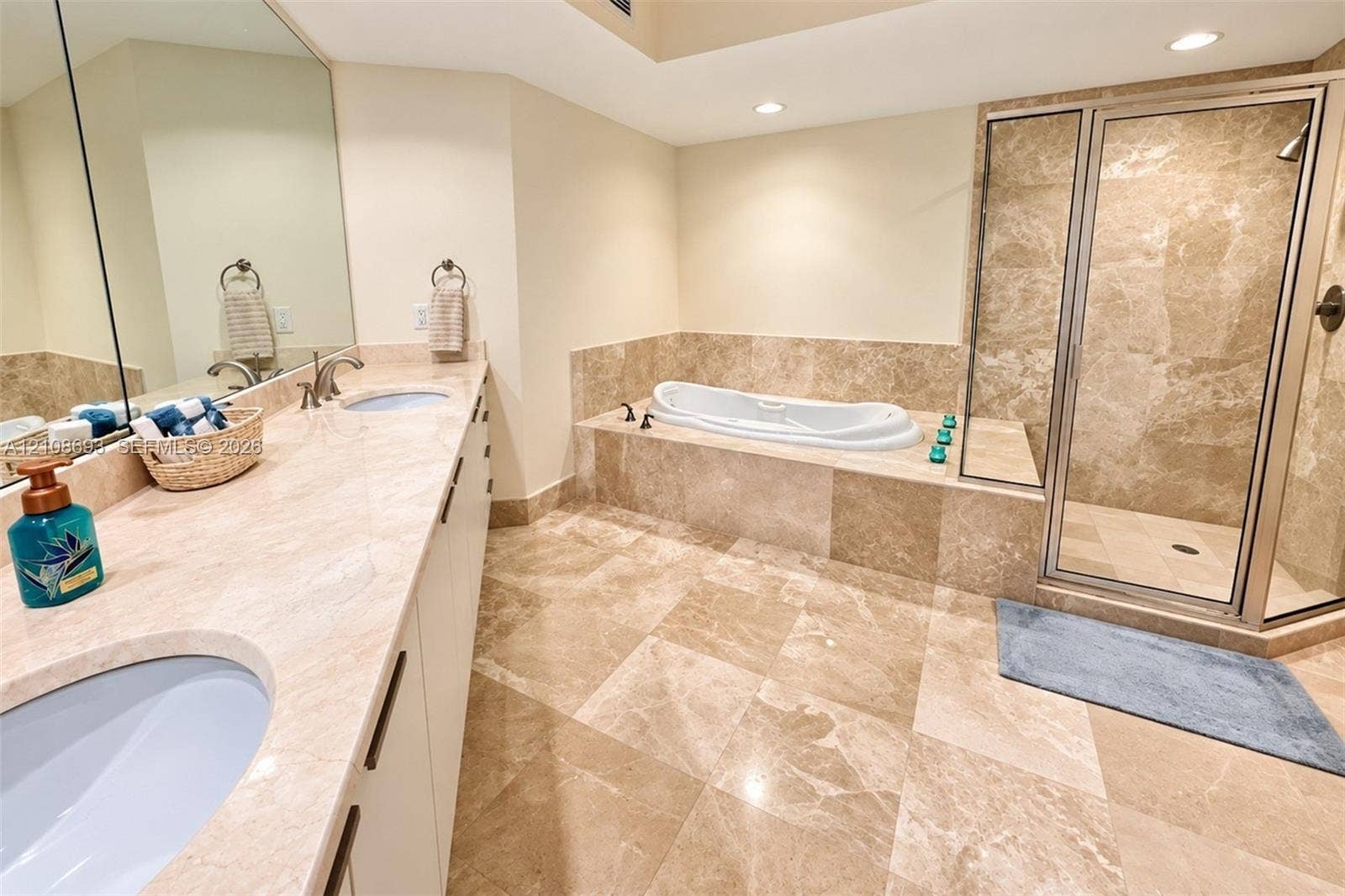 231 Riverside Drive, #1210, Daytona Beach, Daytona Beach, FL 32117 Bathroom featuring natural stone tile flooring, an expansive vanity with stone countertop, an inset soaking tub, and a separate glass-enclosed shower