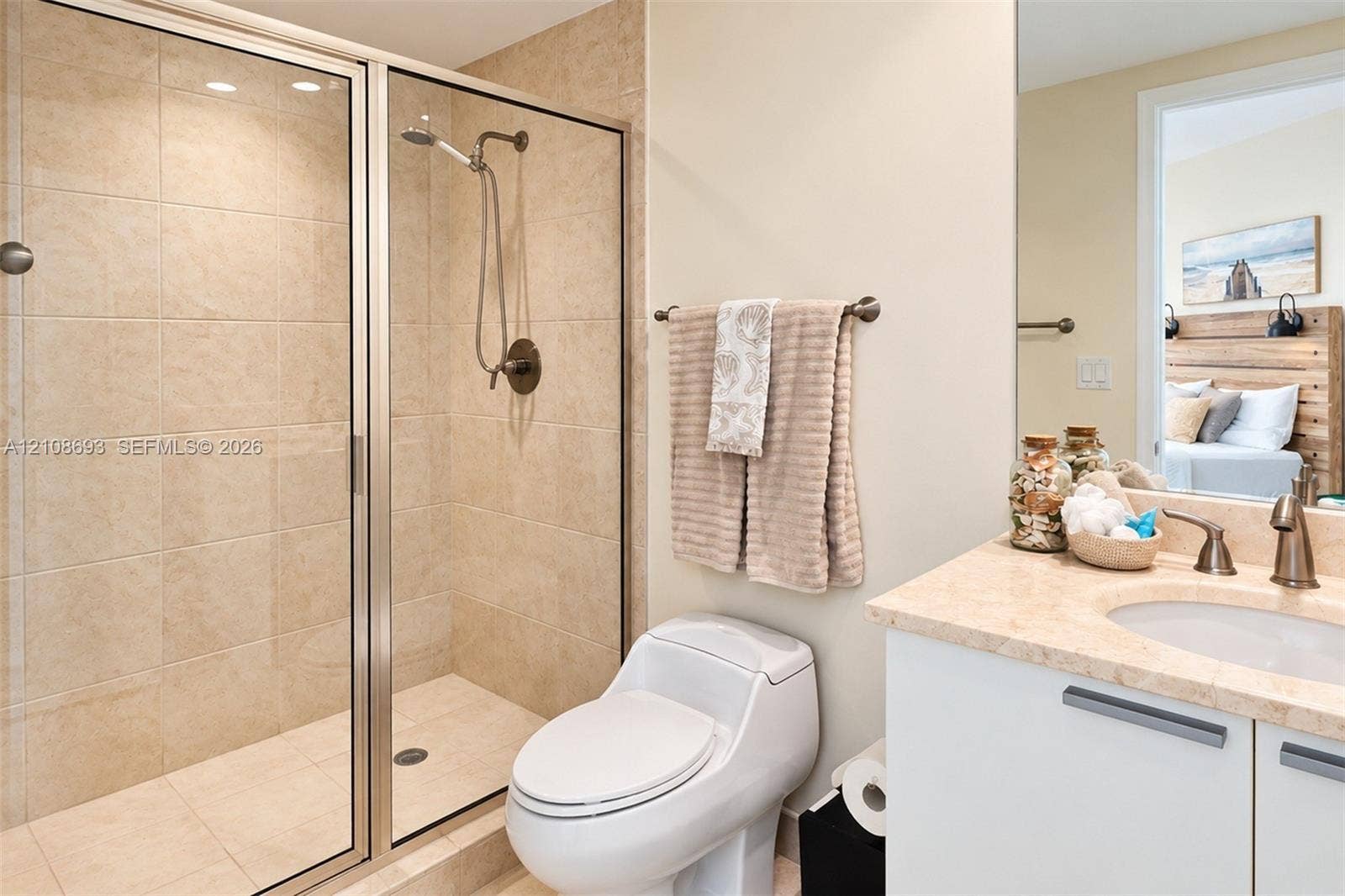 231 Riverside Drive, #1210, Daytona Beach, Daytona Beach, FL 32117 Bathroom featuring a glass-enclosed shower with neutral wall tiling, stone-surface vanity countertop, undermount sink, and metal-finish plumbing fixtures