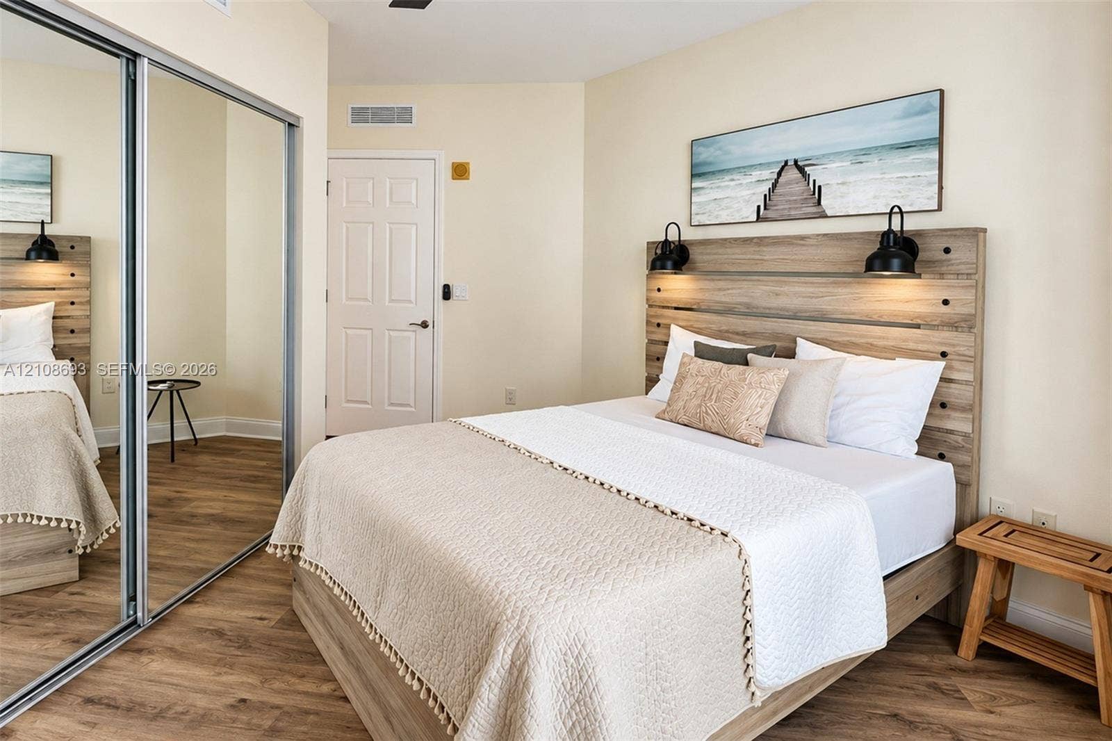 231 Riverside Drive, #1210, Daytona Beach, Daytona Beach, FL 32117 Wood-finish flooring, full-height mirrored sliding closet doors, integrated wood-tone headboard, and dual wall-mounted light fixtures