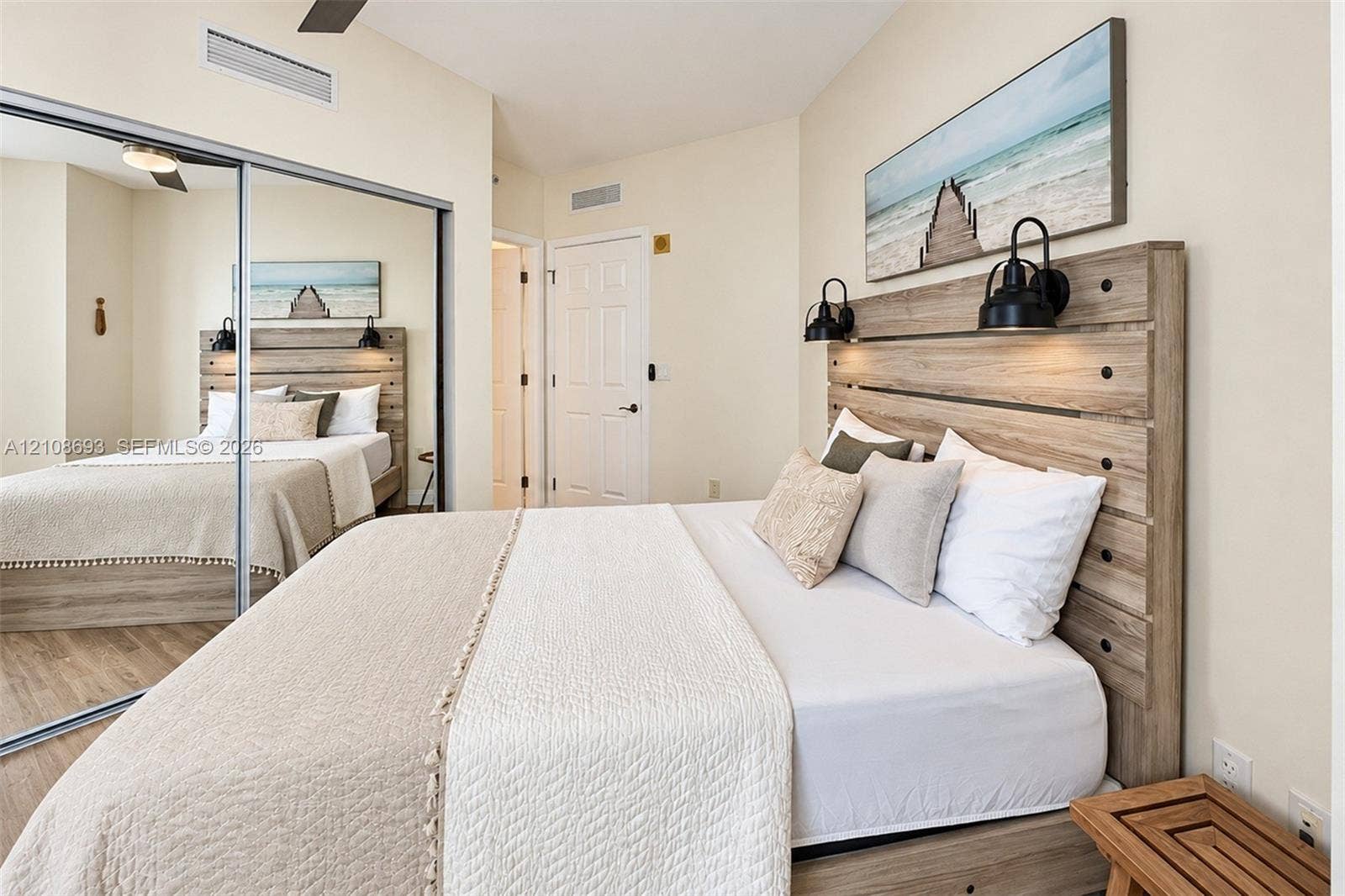231 Riverside Drive, #1210, Daytona Beach, Daytona Beach, FL 32117 Room featuring wood-finish flooring, a full-length mirrored closet, and two wall-mounted metal light fixtures