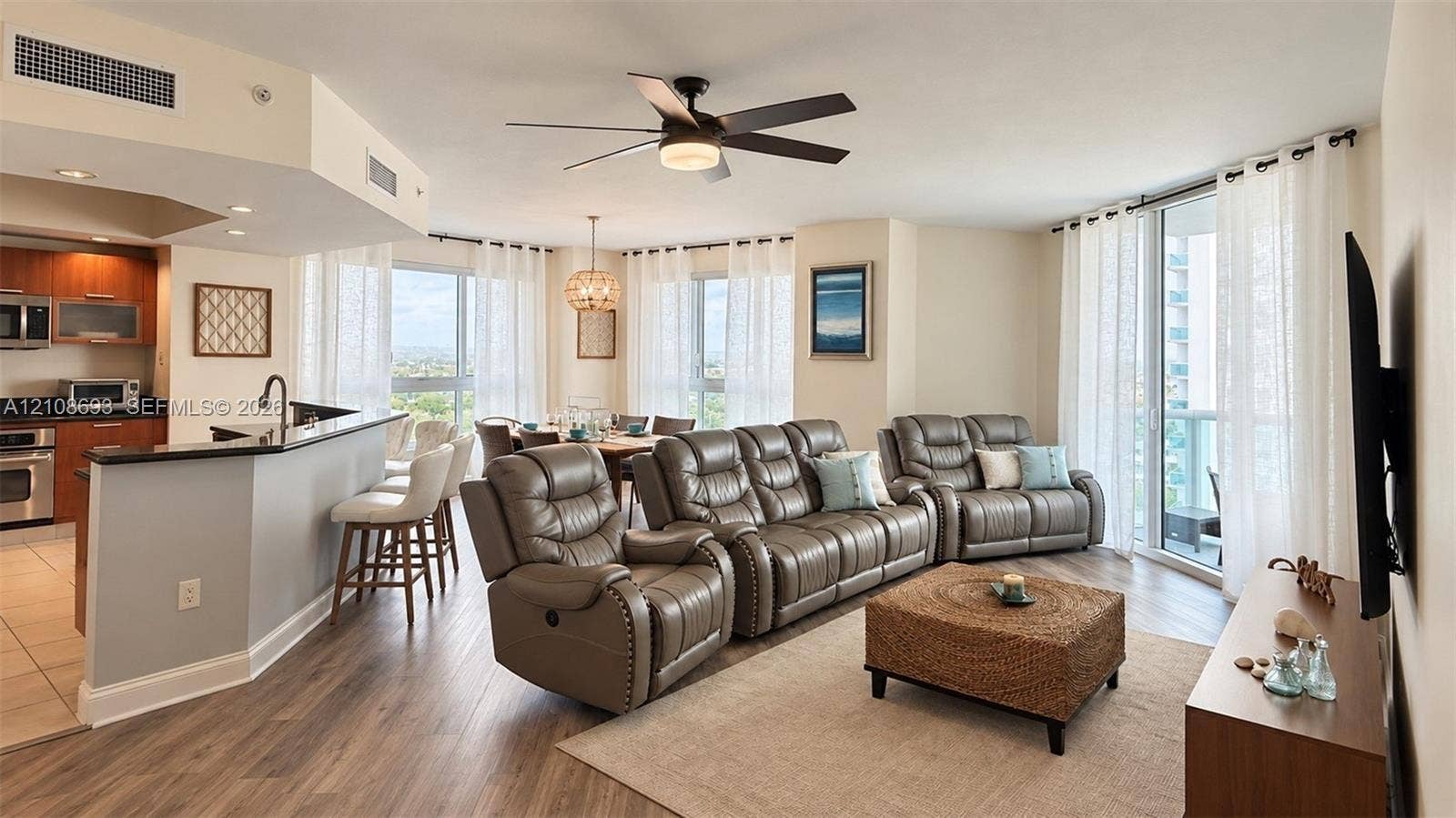 231 Riverside Drive, #1210, Daytona Beach, Daytona Beach, FL 32117 Open-concept area featuring wood-finish flooring, a kitchen breakfast bar with dark countertops, floor-to-ceiling windows, and a central ceiling fan