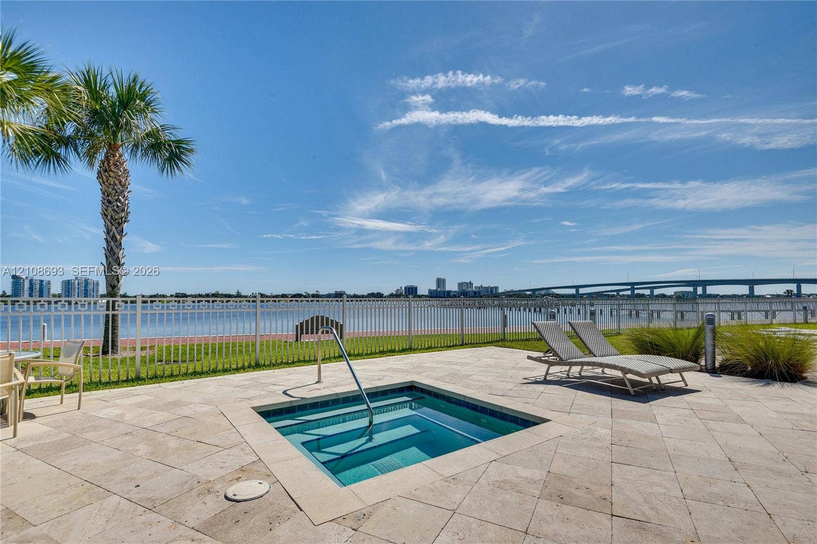231 Riverside Drive, #1210, Daytona Beach, Daytona Beach, FL 32117 In-ground spa with a metal handrail, stone tile deck, and metal perimeter fencing overlooking a waterfront bulkhead