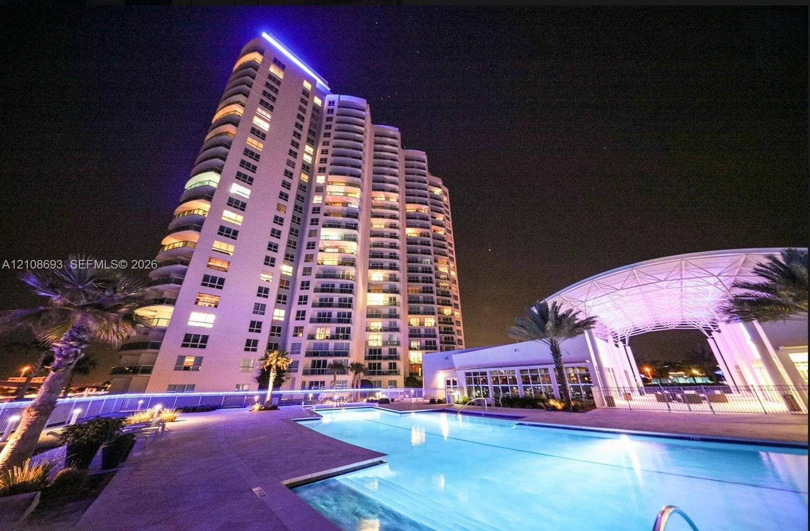231 Riverside Drive, #1210, Daytona Beach, Daytona Beach, FL 32117 High-rise residential tower featuring tiered balconies, a sprawling swimming pool, expansive pool deck, and a covered pavilion with structural framework