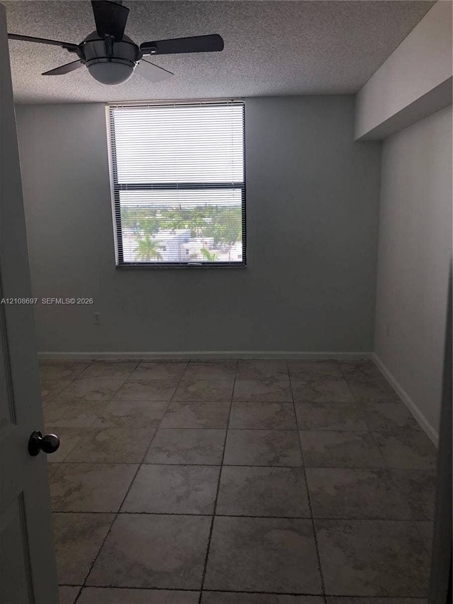 Neutral-toned tile flooring, multi-light ceiling fan, and large picture window