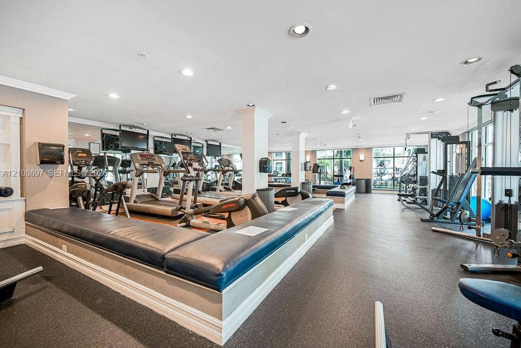 Fitness center featuring rubber flooring, recessed lighting, mirrored walls, and a built-in upholstered platform bench