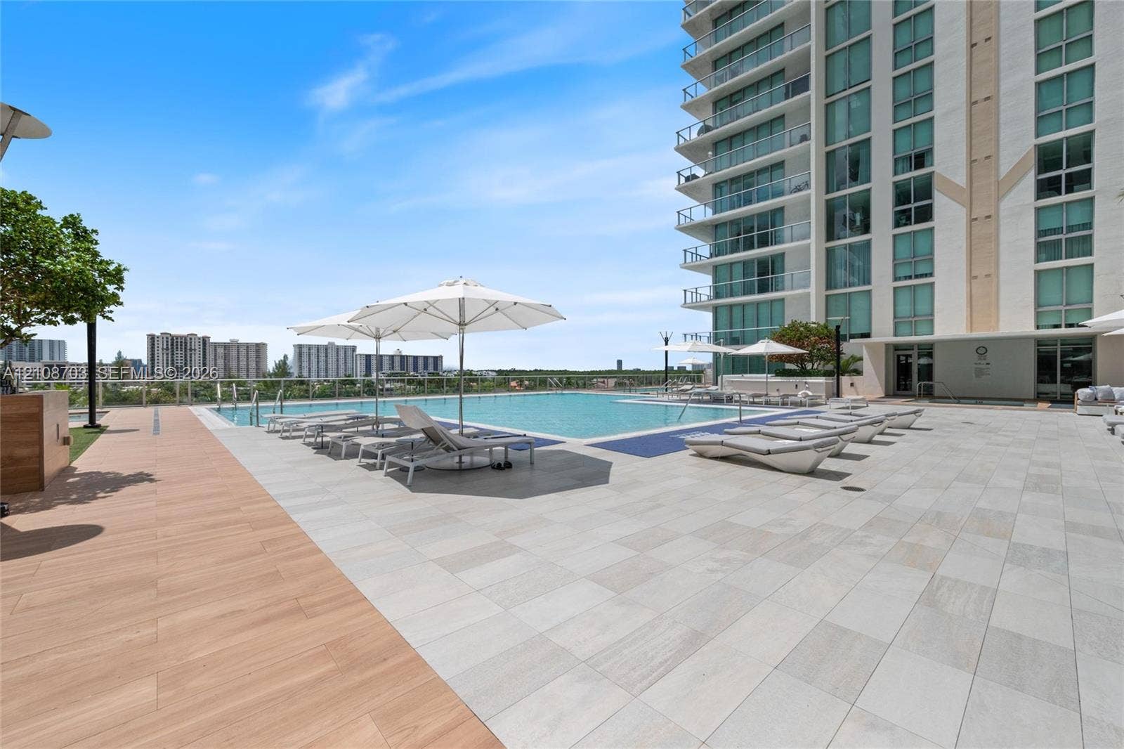 300 Sunny Isles Boulevard, #4-1501, Sunny Isles Beach, Sunny Isles Beach, FL 33160 Elevated swimming pool featuring stone tile decking, wood-finish flooring accents, and a glass panel railing