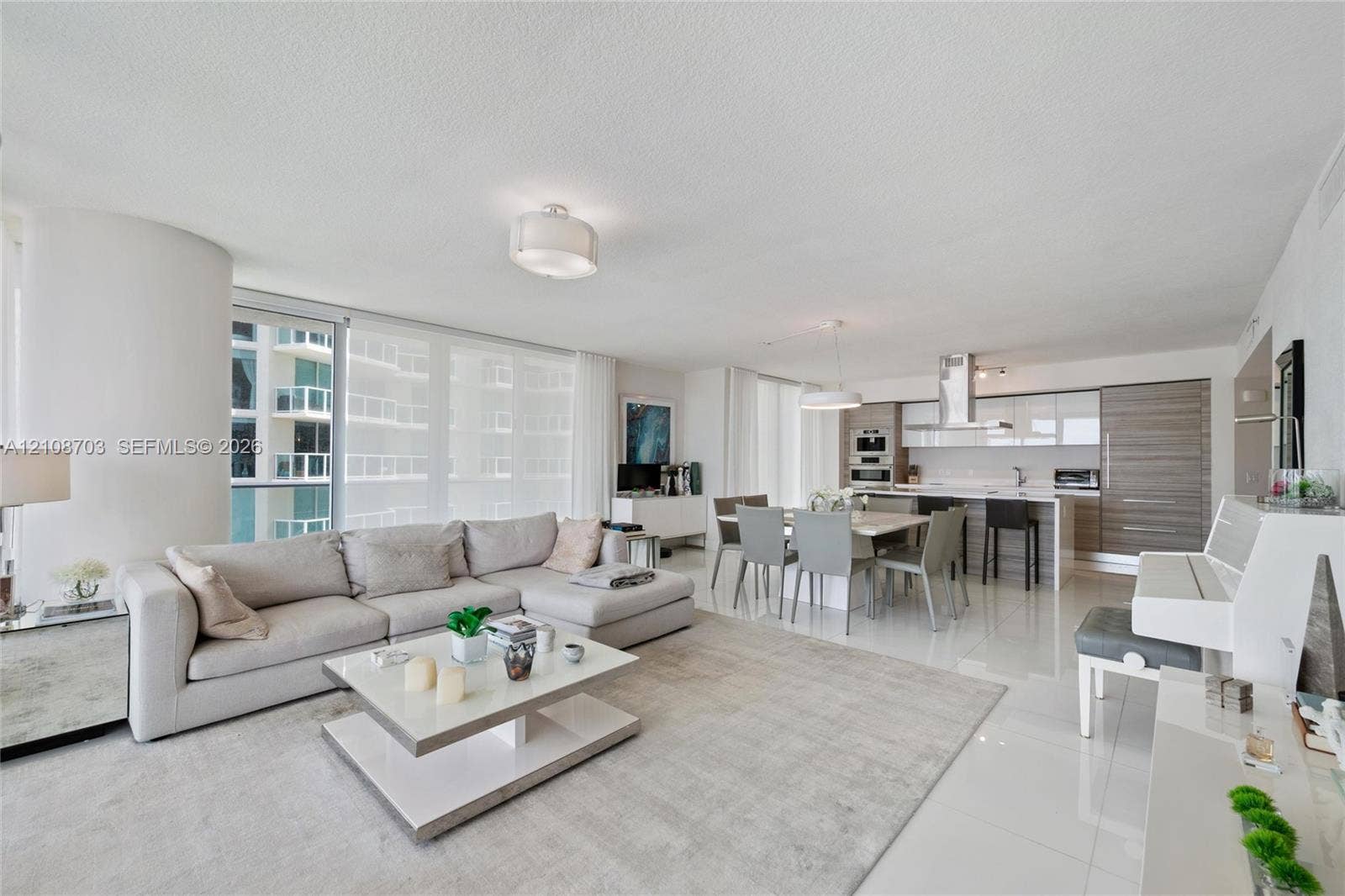 300 Sunny Isles Boulevard, #4-1501, Sunny Isles Beach, Sunny Isles Beach, FL 33160 Open-concept living area featuring large-format tile flooring, floor-to-ceiling windows, modern cabinetry with wood-finish and high-gloss accents, and stainless steel built-in appliances