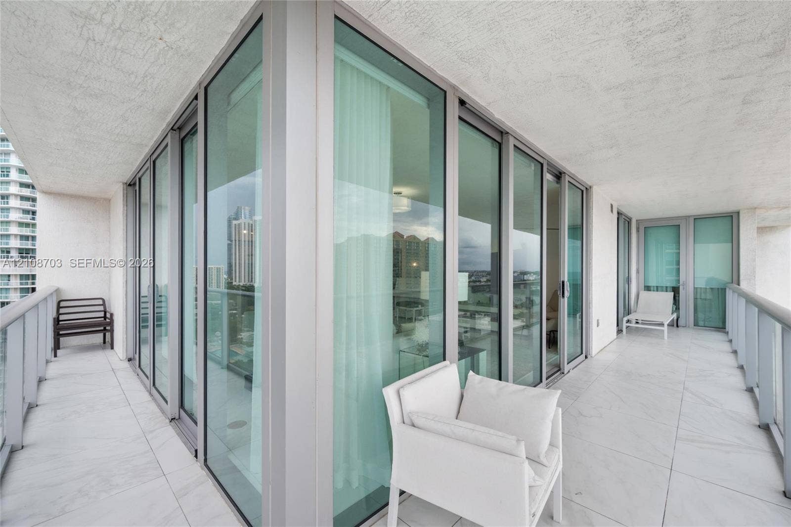 300 Sunny Isles Boulevard, #4-1501, Sunny Isles Beach, Sunny Isles Beach, FL 33160 Wrap-around balcony featuring large-format tile flooring, floor-to-ceiling glass panel sliding doors, and metal railings