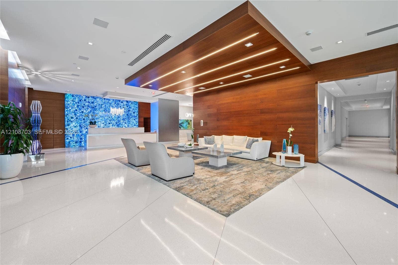 300 Sunny Isles Boulevard, #4-1501, Sunny Isles Beach, Sunny Isles Beach, FL 33160 Lobby featuring white tile flooring, wood-paneled walls and ceiling accent, integrated linear lighting, and a backlit blue stone focal wall