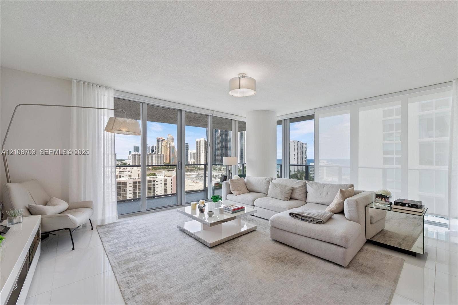 300 Sunny Isles Boulevard, #4-1501, Sunny Isles Beach, Sunny Isles Beach, FL 33160 Living area featuring floor-to-ceiling glass windows, polished tile flooring, a cylindrical structural pillar, and glass balcony railings