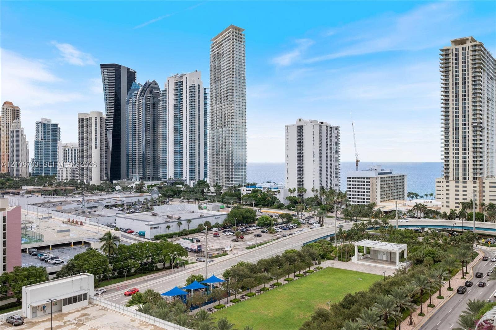 300 Sunny Isles Boulevard, #4-1501, Sunny Isles Beach, Sunny Isles Beach, FL 33160 Urban landscape featuring high-rise buildings, a maintained green space with a pavilion, and coastal horizon