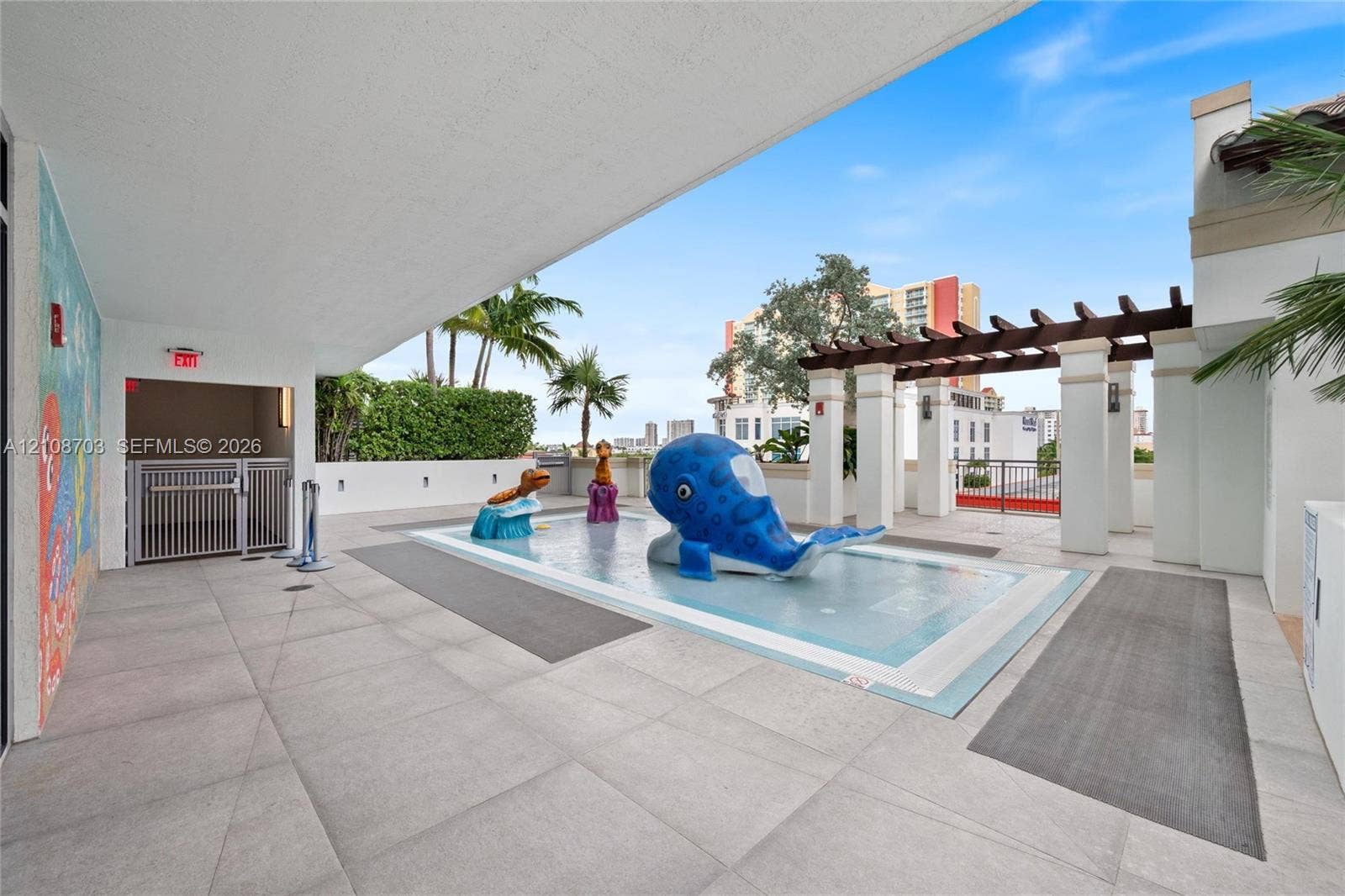 300 Sunny Isles Boulevard, #4-1501, Sunny Isles Beach, Sunny Isles Beach, FL 33160 Splash pad featuring built-in water play structures, tile surround, stone-finish patio, and a covered timber pergola