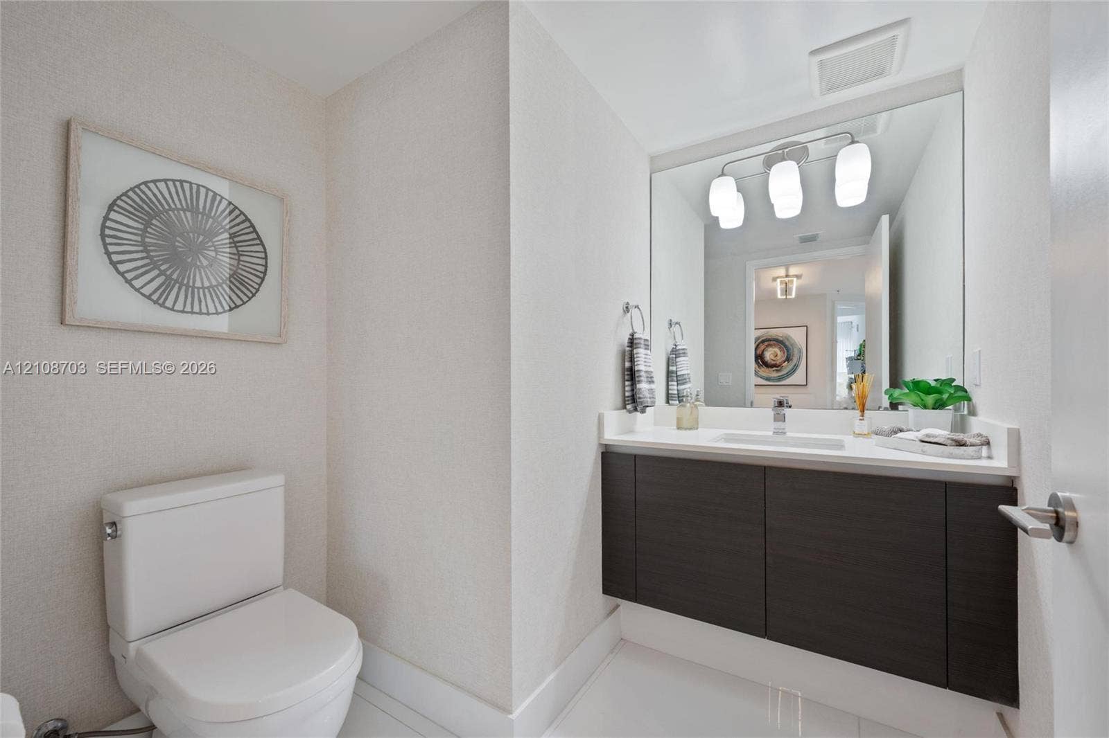 300 Sunny Isles Boulevard, #4-1501, Sunny Isles Beach, Sunny Isles Beach, FL 33160 Wall-mounted floating vanity with dark wood-finish cabinetry, solid-surface countertop, rectangular undermount sink, and three-light integrated vanity fixture