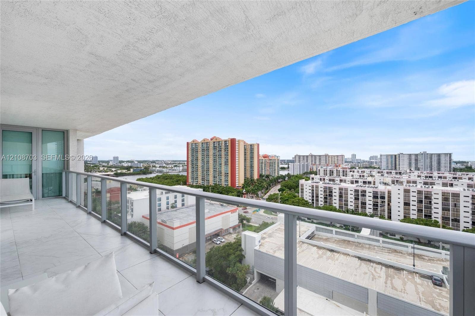 300 Sunny Isles Boulevard, #4-1501, Sunny Isles Beach, Sunny Isles Beach, FL 33160 Covered balcony with large-format tile flooring and a glass-paneled railing